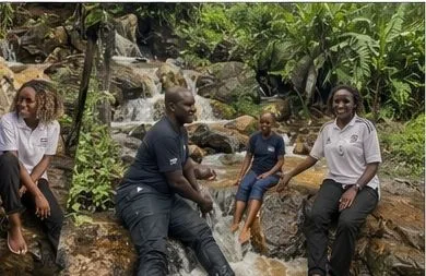 Four people sitting on rocks beside water stepping down through vegetation